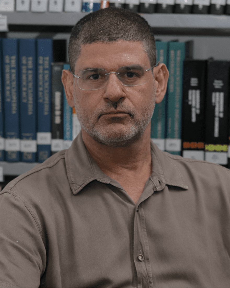 Fabiano Santos diante de uma estante de livros no IESP-UERJ.